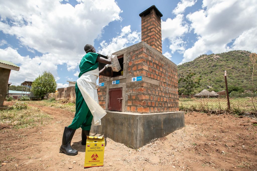Health worker disposing of waste in Kaabong Uganda
