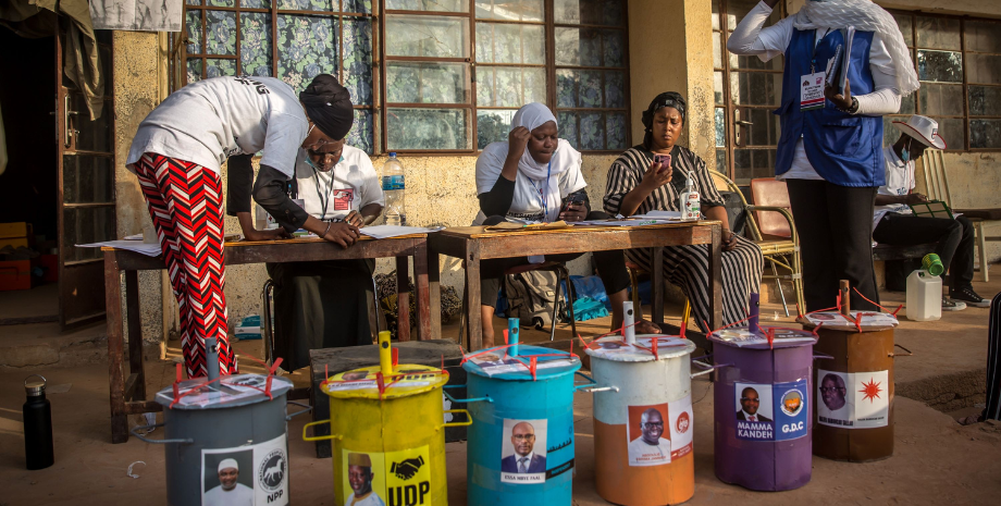A Gambian election commission worker stands beside ballot boxes as he arrives to prepare a polling station ahead of the presidential election in Banjul, Gambia.