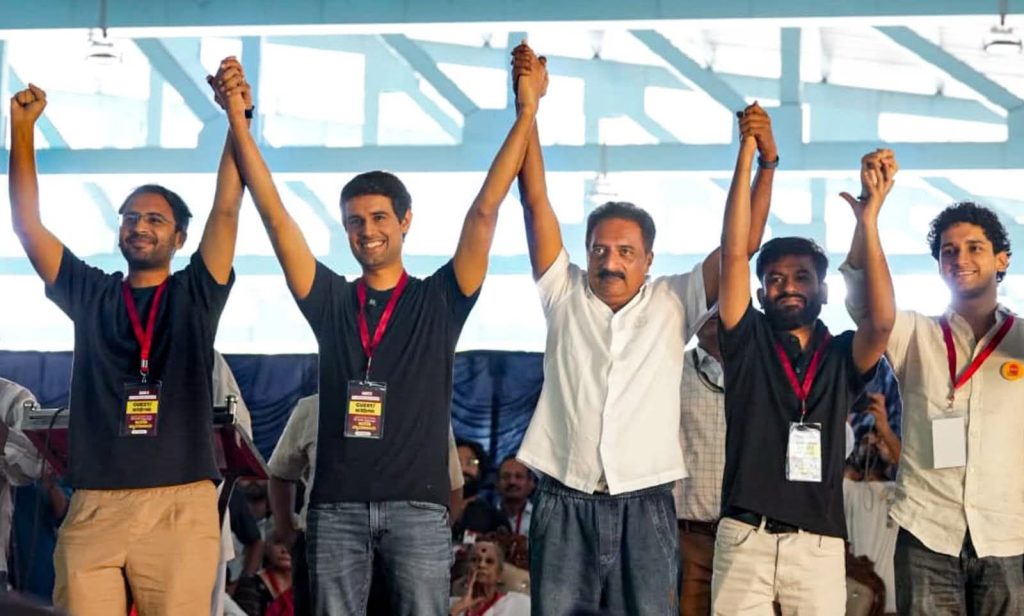 Cockroach Janta Party leaders and guests raise joined hands on stage at a rally.