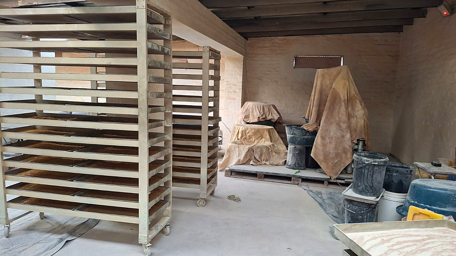 Steel drying racks loaded with trays inside the shed on the Hekpoort farm, near Krugersdorp, where police say they found a suspected Mandrax and ecstasy laboratory on 8 October 2026. Five men have been charged and are presumed innocent.