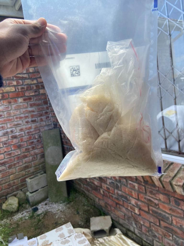 Police hold up an evidence bag of a suspected drug seized in Gqeberha, where the drugs found have an estimated street value of more than R9.7 million.