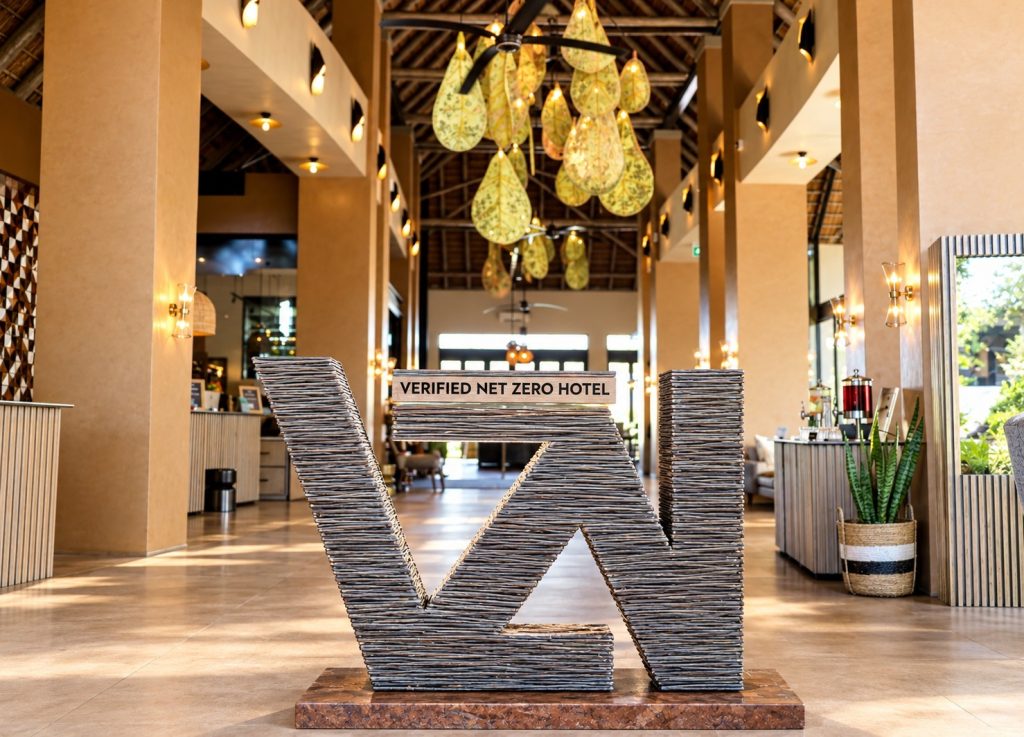 A Verified Net Zero Hotel sign in the lobby of Radisson Safari Hotel Hoedspruit. The hotel combines rooftop solar, renewable energy certificates and an electrified kitchen, with remaining emissions covered by carbon credits from a South African grassland restoration project.
