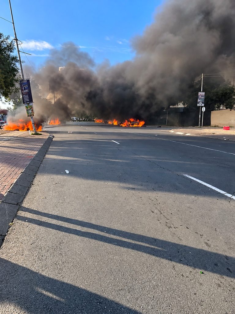 Thick smoke rises from burning vehicles in the road during the unrest that followed the Home Affairs asylum directive.